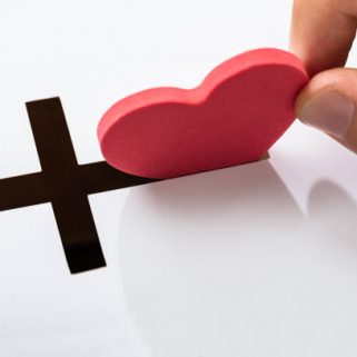 Hand Inserting Heart Shape In Crucifix Slot On White Background